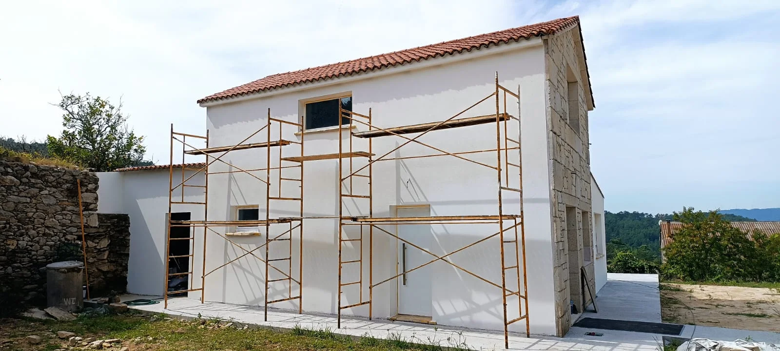 Fachada blanca con andamio. Vista de la vivienda durante el trabajo exterior.