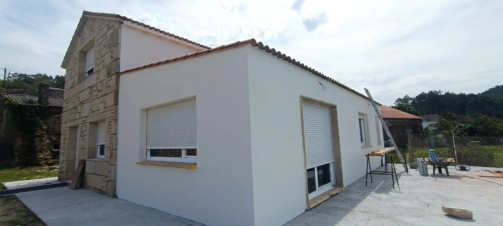 Fachada blanca, vista en perspectiva. Una vista amplia del acabado exterior y de las protecciones de ventanas.