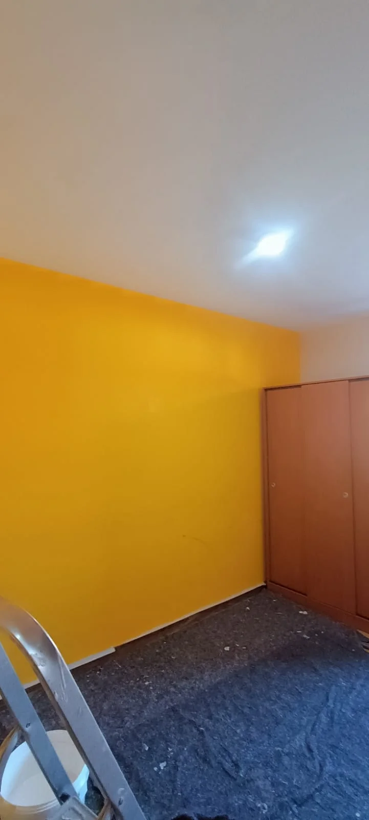Pared de acento amarillo. Pared amarilla en una habitación con el suelo protegido.