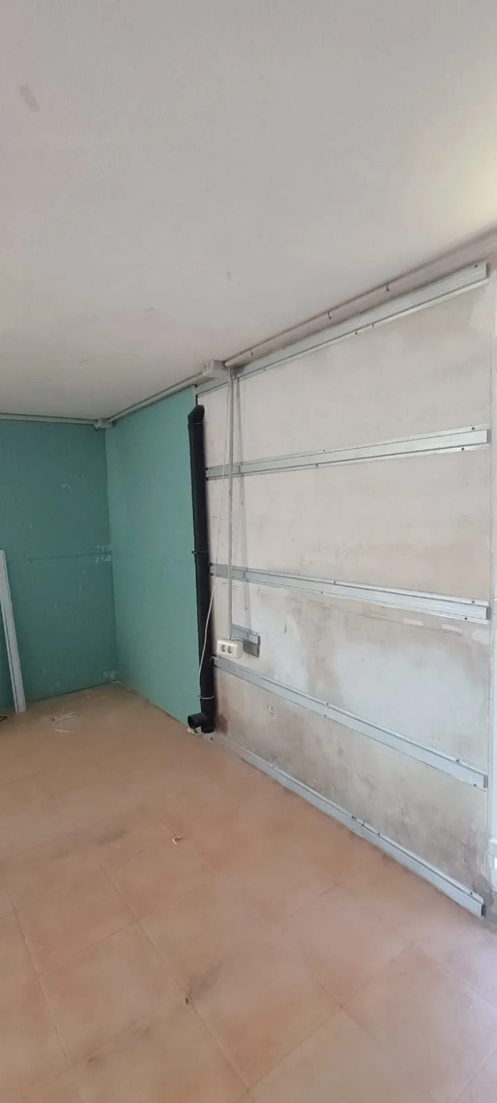 Perfilería antes de cerrar la pared. Perfiles metálicos visibles en un paño pendiente de colocar placas, junto a otro paño ya revestido.